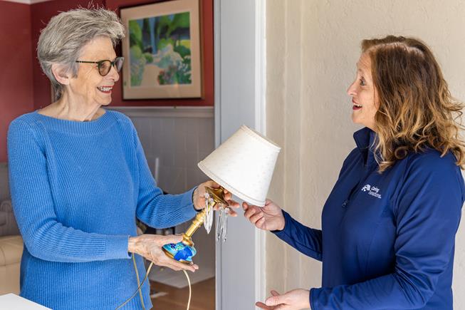 senior moving client handing lamp to move manager